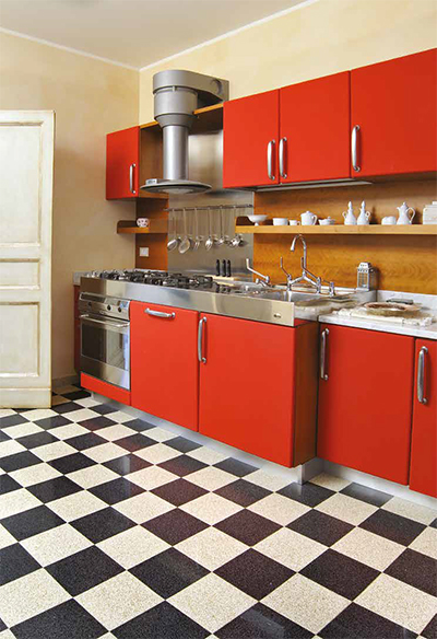 In deze moderne keuken met rode kasten werd gekozen voor een dambord in terrazzo tegels wit/zwart.