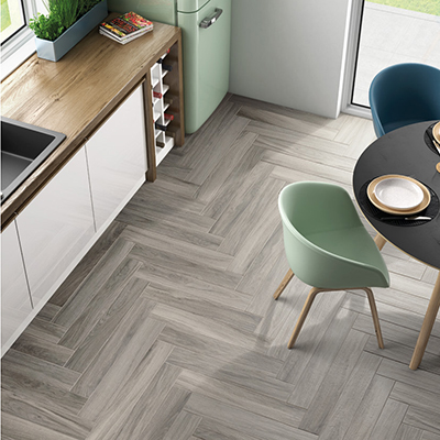 In deze moderne keuken in pastel groen werd gekozen voor grijs keramisch parket. De parkettegels werden in visgraat geplaatst.