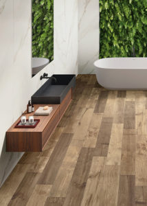 Moderne hotel chique badkamer met op de wand marmerlook tegels in combinatie met op de vloer donker keramisch parket in notenhout.
